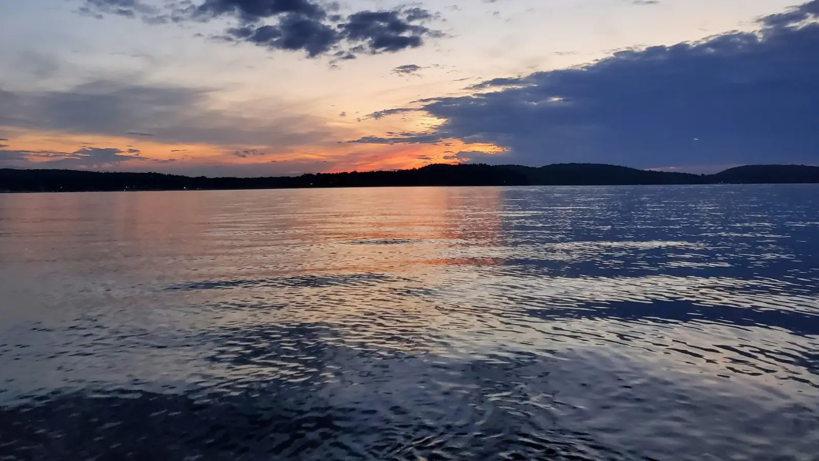 Sunset over open lake water representing bass fishing destinations across the United States